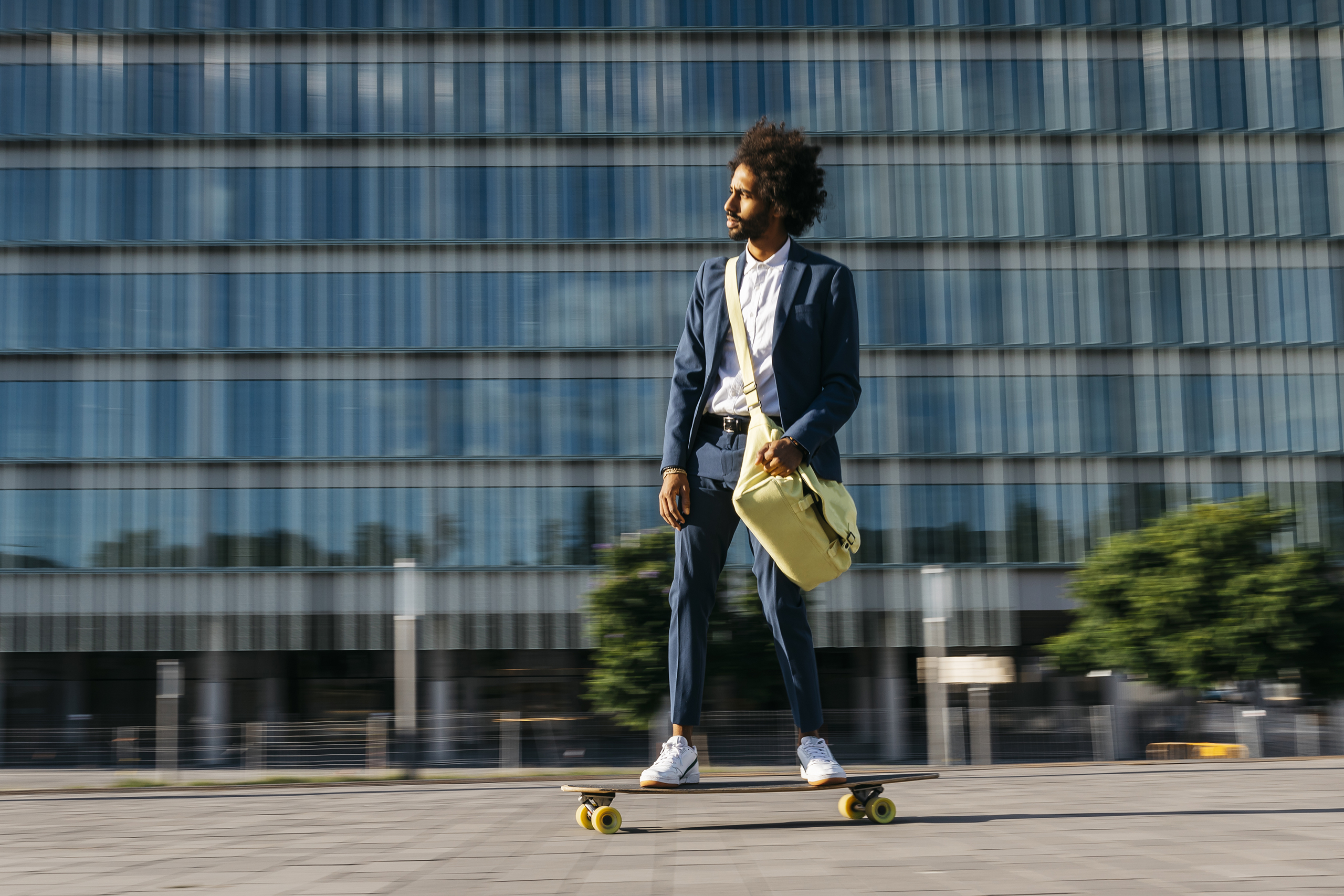 Spain, Barcelona, young businessman riding skateboard in the city